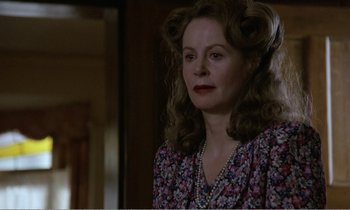 Movie still from “Hope and Glory” (1987), directed by John Boorman – A woman in a floral print dress with her hair in a bun; Close Up shot, Low angle