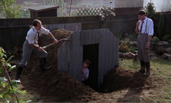 Movie still from “Hope and Glory” (1987), directed by John Boorman – Two men and a boy are digging a hole in the ground; Wide shot, High angle