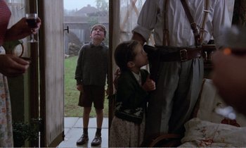 Movie still from “Hope and Glory” (1987), directed by John Boorman – A young boy and a little girl standing next to each other; Medium shot, Over the shoulder angle