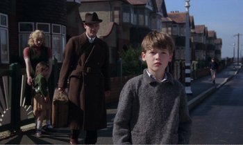 Movie still from “Hope and Glory” (1987), directed by John Boorman – A man and a boy walking down a street; Medium shot, Low angle