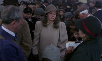 Movie still from “Hope and Glory” (1987), directed by John Boorman – A crowd of people wearing hats and coats; Medium shot, Over the shoulder angle