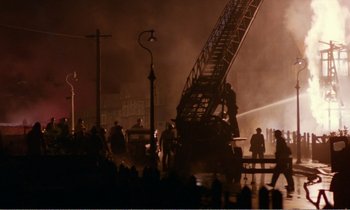 Movie still from “Hope and Glory” (1987), directed by John Boorman – A group of people standing next to a fire truck; Extreme Wide shot, High angle