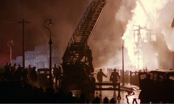 Movie still from “Hope and Glory” (1987), directed by John Boorman – A group of people standing next to a fire hydrant; Extreme Wide shot, Low angle