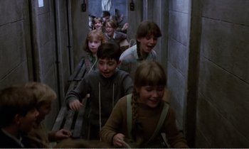 Movie still from “Hope and Glory” (1987), directed by John Boorman – A group of children walking down a hall way; Medium shot, High angle