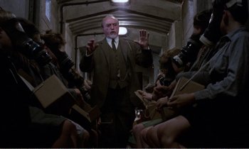 Movie still from “Hope and Glory” (1987), directed by John Boorman – An older man in a suit and tie surrounded by people; Wide shot, Low angle