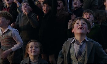 Movie still from “Hope and Glory” (1987), directed by John Boorman – A group of children standing next to each other in a crowd; Medium shot, Low angle