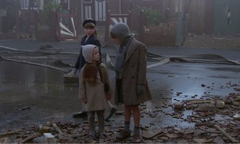 Movie still from “Hope and Glory” (1987), directed by John Boorman – A group of children standing in the middle of a street; Wide shot, High angle