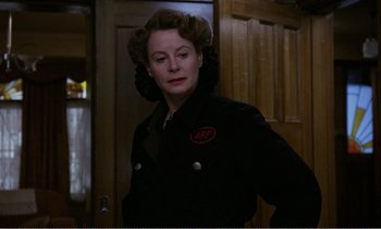 Movie still from “Hope and Glory” (1987), directed by John Boorman – A woman in a black jacket standing next to a door; Close Up shot, Low angle