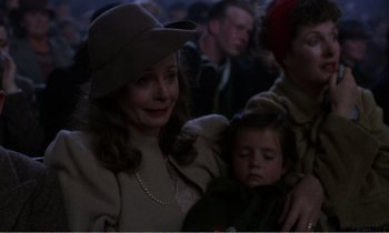 Movie still from “Hope and Glory” (1987), directed by John Boorman – A woman and a little girl are sitting in a crowd of people; Close Up shot, Over the shoulder angle