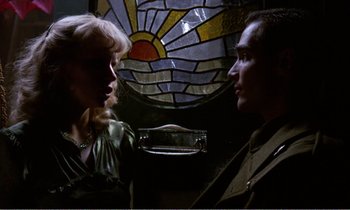 Movie still from “Hope and Glory” (1987), directed by John Boorman – A man and a woman standing next to each other in front of a stained glass window; Medium shot, Low angle