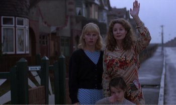 Movie still from “Hope and Glory” (1987), directed by John Boorman – Two women and a girl standing on a sidewalk; Medium shot, Low angle