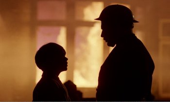 Movie still from “Hope and Glory” (1987), directed by John Boorman – A man and a boy are standing next to each other in front of a window; Close Up shot, Over the shoulder angle