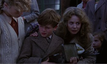 Movie still from “Hope and Glory” (1987), directed by John Boorman – A boy and a woman are sitting next to each other; Medium shot, Over the shoulder angle