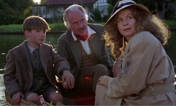 Movie still from “Hope and Glory” (1987), directed by John Boorman – A group of people sitting next to each other on a boat; Medium shot, Over the shoulder angle