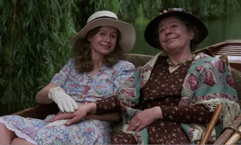 Movie still from “Hope and Glory” (1987), directed by John Boorman – Two women sitting next to each other on a bench; Medium shot, High angle