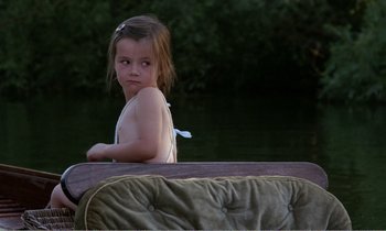Movie still from “Hope and Glory” (1987), directed by John Boorman – A little girl sitting in a boat on the water; Medium shot, High angle