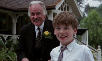Movie still from “Hope and Glory” (1987), directed by John Boorman – An older man standing next to a young boy; Close Up shot, Low angle