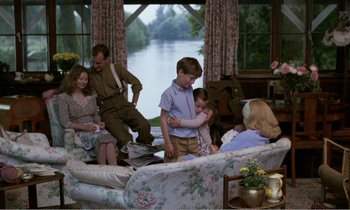 Movie still from “Hope and Glory” (1987), directed by John Boorman – A group of people sitting around a living room; Wide shot, High angle