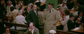 Movie still from “Hopscotch” (1980), directed by Ronald Neame – A group of men standing next to each other in a room; Medium shot, High angle