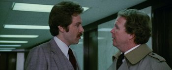 Movie still from “Hopscotch” (1980), directed by Ronald Neame – Two men in suits talking to each other in an office building; Close Up shot, Over the shoulder angle