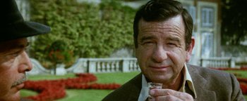 Movie still from “Hopscotch” (1980), directed by Ronald Neame – An older man holding a shot glass in his hand; Close Up shot, High angle