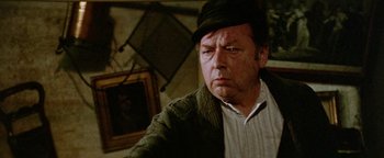 Movie still from “Hopscotch” (1980), directed by Ronald Neame – An older man wearing a hat and a sweater; Close Up shot, Over the shoulder angle