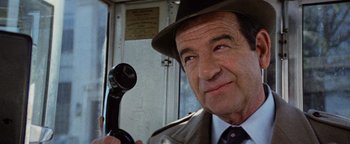 Movie still from “Hopscotch” (1980), directed by Ronald Neame – An older man wearing a hat and holding a phone; Close Up shot, Low angle