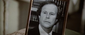 Movie still from “Hopscotch” (1980), directed by Ronald Neame – An old black and white photo of a man in a suit; Close Up shot, Over the shoulder angle