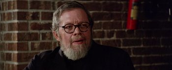 Movie still from “Hopscotch” (1980), directed by Ronald Neame – An older man with a beard wearing glasses and a suit; Close Up shot, Over the shoulder angle