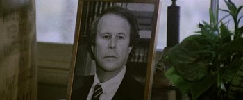 Movie still from “Hopscotch” (1980), directed by Ronald Neame – An old photo of a man in a suit and tie; Close Up shot, Over the shoulder angle