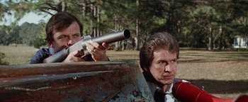 Movie still from “Hopscotch” (1980), directed by Ronald Neame – Two men in suits and ties are holding guns; Medium shot, Low angle