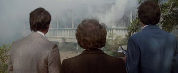 Movie still from “Hopscotch” (1980), directed by Ronald Neame – A man in a brown jacket is looking out of a window; Medium shot, Over the shoulder angle