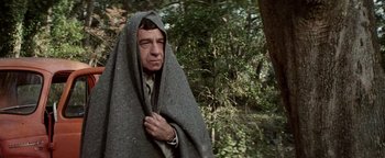 Movie still from “Hopscotch” (1980), directed by Ronald Neame – A man wrapped in a blanket in a wooded area; Medium shot, Low angle