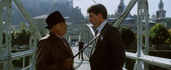 Movie still from “Hopscotch” (1980), directed by Ronald Neame – Two men in suits and hats are on a bridge; Medium shot, Low angle