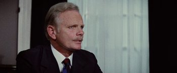 Movie still from “Hopscotch” (1980), directed by Ronald Neame – An older man wearing a suit and tie; Close Up shot, Low angle