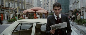 Movie still from “Hopscotch” (1980), directed by Ronald Neame – A man standing next to a white car holding a newspaper; Medium shot, Low angle