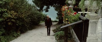 Movie still from “Hopscotch” (1980), directed by Ronald Neame – A man walking down a path next to a body of water; Wide shot, High angle