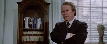 Movie still from “Hopscotch” (1980), directed by Ronald Neame – A man standing in front of a book shelf; Medium shot, Low angle