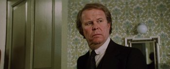 Movie still from “Hopscotch” (1980), directed by Ronald Neame – A person wearing a suit and tie; Close Up shot, Low angle