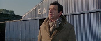 Movie still from “Hopscotch” (1980), directed by Ronald Neame – A man wearing a coat and a neck scarf; Medium shot, Low angle