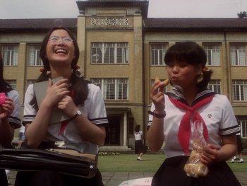 Movie still from “House” (1977), directed by Nobuhiko Ôbayashi – Two young women in school uniforms are eating food; Medium shot, Low angle