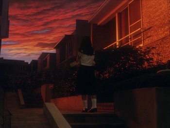 Movie still from “House” (1977), directed by Nobuhiko Ôbayashi – A woman standing on steps in front of a building at sunset; Extreme Wide shot, Low angle