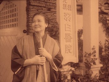 Movie still from “House” (1977), directed by Nobuhiko Ôbayashi – An old photo of an older woman holding a cane; Medium shot, Low angle