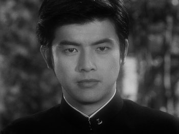 Movie still from “House” (1977), directed by Nobuhiko Ôbayashi – A black and white photo of a man in a suit; Close Up shot, Low angle