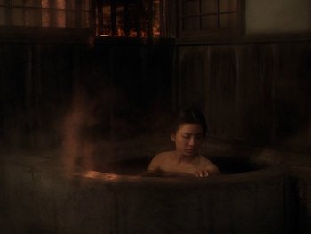 Movie still from “House” (1977), directed by Nobuhiko Ôbayashi – A woman sitting in a hot tub in a dark room; Wide shot, High angle