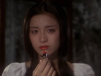 Movie still from “House” (1977), directed by Nobuhiko Ôbayashi – A young woman putting lipstick on in a dark room; Close Up shot, Over the shoulder angle