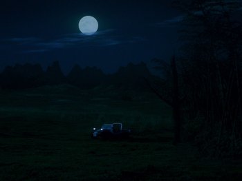 Movie still from “House” (1977), directed by Nobuhiko Ôbayashi – A car is parked in the middle of a field at night with a full moon in the background; Extreme Wide shot, High angle