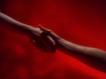 Movie still from “House” (1977), directed by Nobuhiko Ôbayashi – Two people shaking hands over a red background; Extreme Close Up shot, Overhead angle