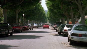 Movie still from “House Party 2” (1991), directed by Doug McHenry – Cars parked along a street lined with trees; Extreme Wide shot, Low angle