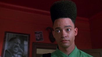 Movie still from “House Party 2” (1991), directed by Doug McHenry – A man with a very large hair style on top of his head; Close Up shot, Low angle